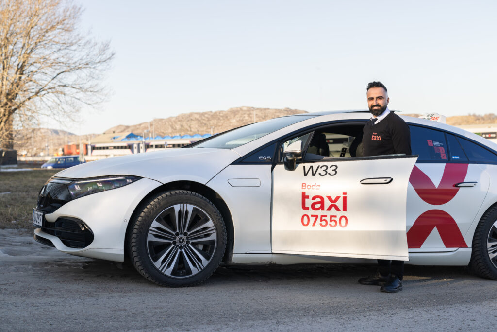 Hawar Chooly foran sin taxi forteller om gode dager på jobb.